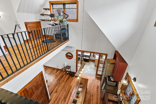 stairs featuring hardwood / wood-style flooring, an AC wall unit, baseboards, and a high ceiling