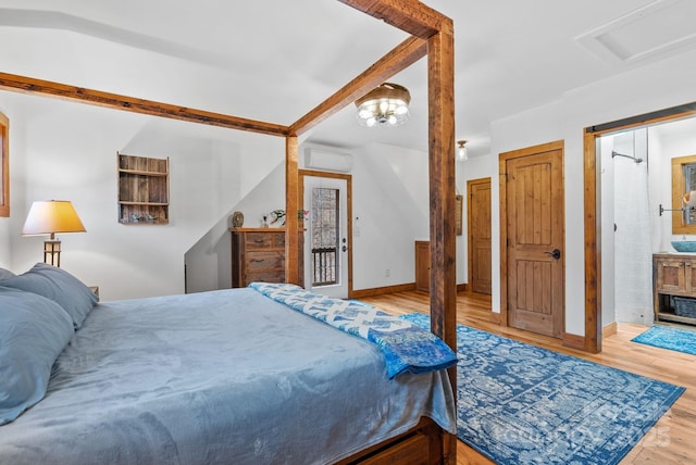 bedroom with baseboards, a wall unit AC, and wood finished floors