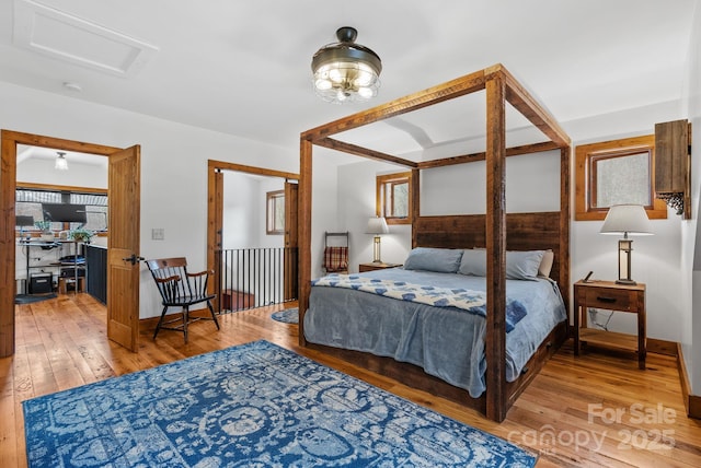 bedroom featuring baseboards, attic access, and light wood-style floors