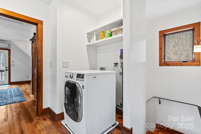 clothes washing area featuring baseboards, washer / clothes dryer, a healthy amount of sunlight, and hardwood / wood-style floors