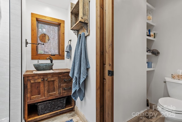 bathroom featuring baseboards, toilet, and vanity