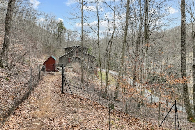 view of yard featuring an outbuilding, a view of trees, and fence