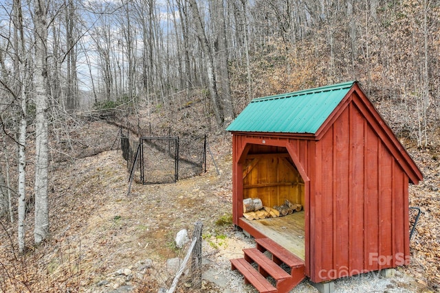 view of shed featuring fence and a view of trees