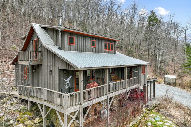 view of front of property featuring a balcony, driveway, metal roof, and board and batten siding