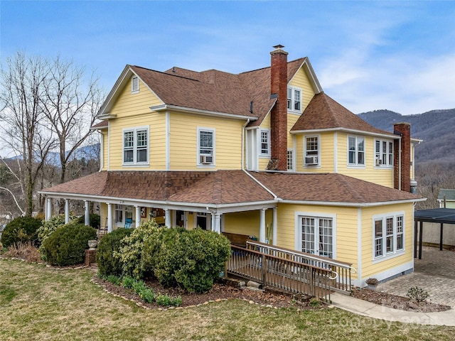 view of front of property with a mountain view, a porch, a chimney, and a shingled roof