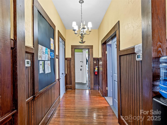 entryway featuring a wainscoted wall, an inviting chandelier, and wood finished floors