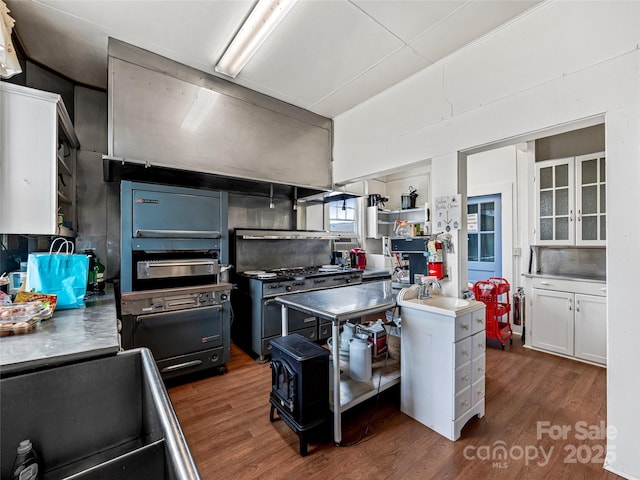 kitchen with range with two ovens, backsplash, dark wood-type flooring, and white cabinetry