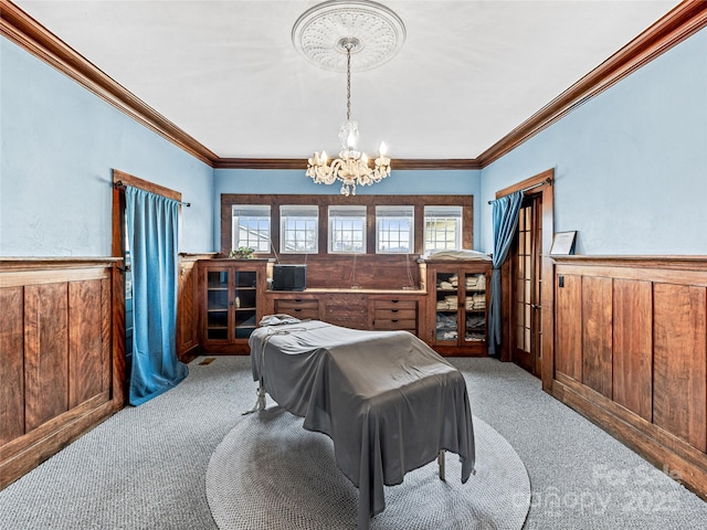 bedroom with wooden walls, a notable chandelier, light colored carpet, and wainscoting