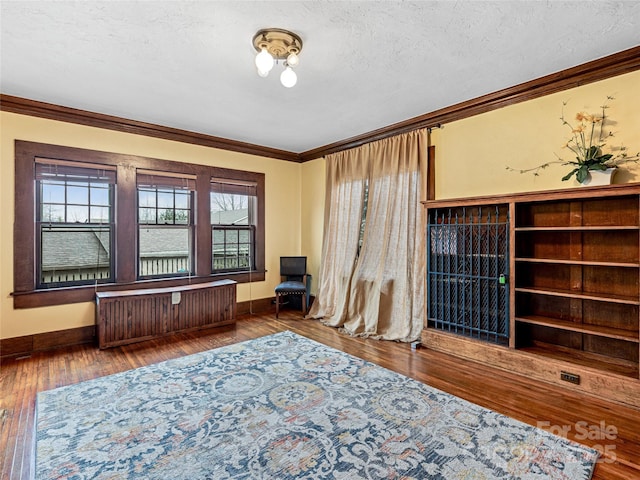 unfurnished room with radiator, crown molding, baseboards, a textured ceiling, and wood-type flooring