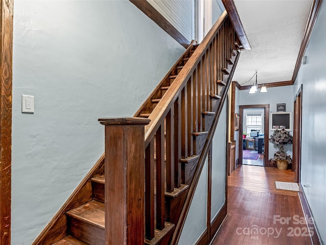 staircase with visible vents, baseboards, ornamental molding, hardwood / wood-style floors, and an inviting chandelier