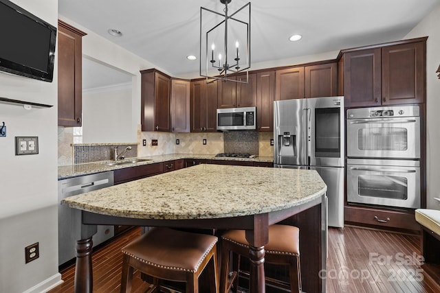 kitchen with dark brown cabinets, a center island, a breakfast bar area, decorative backsplash, and stainless steel appliances