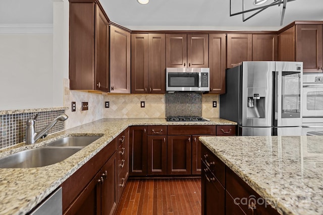 kitchen featuring backsplash, crown molding, dark wood finished floors, stainless steel appliances, and a sink