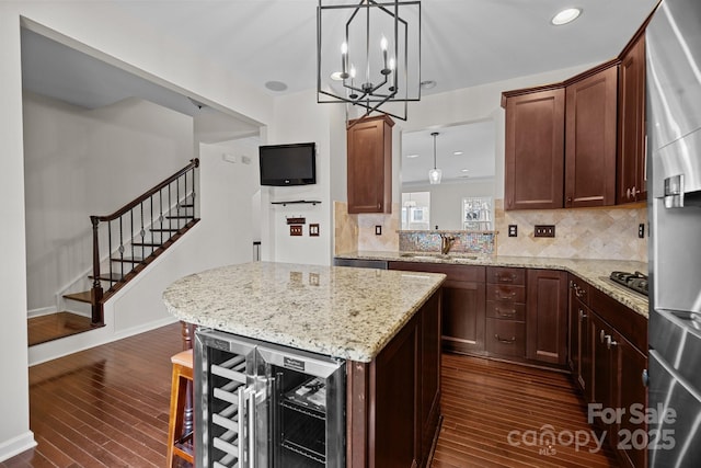 kitchen featuring backsplash, dark wood-type flooring, wine cooler, light stone counters, and a sink