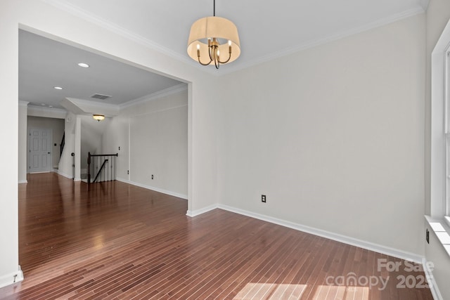 spare room featuring visible vents, baseboards, wood finished floors, and ornamental molding