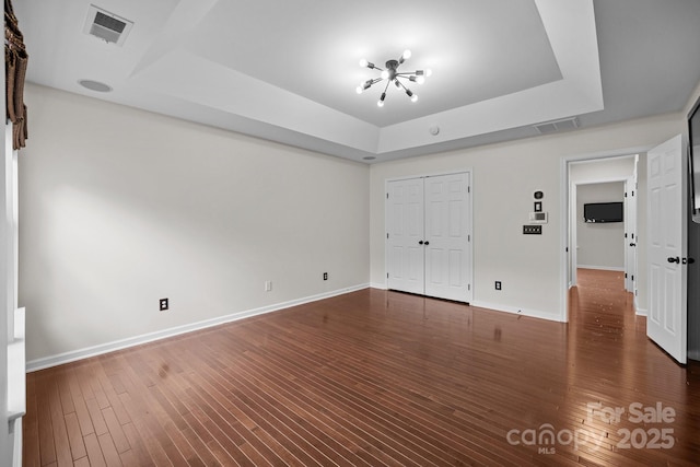 interior space featuring dark wood finished floors, visible vents, baseboards, and a tray ceiling