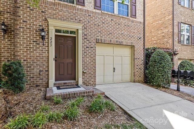 property entrance featuring brick siding, concrete driveway, and a garage