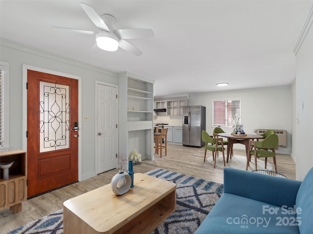 living area featuring an AC wall unit, light wood-type flooring, a ceiling fan, and ornamental molding