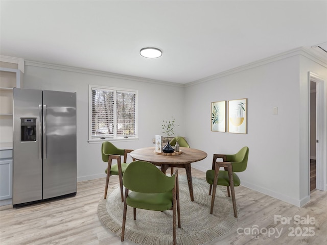 dining space featuring light wood-style floors, baseboards, and ornamental molding