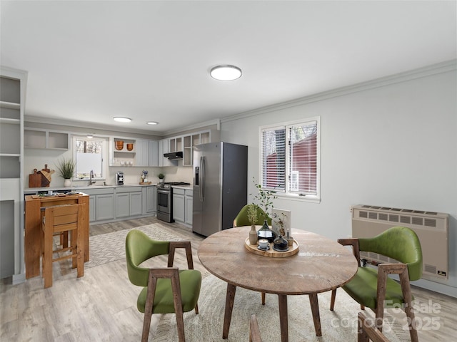 dining room with heating unit, light wood-style floors, and crown molding