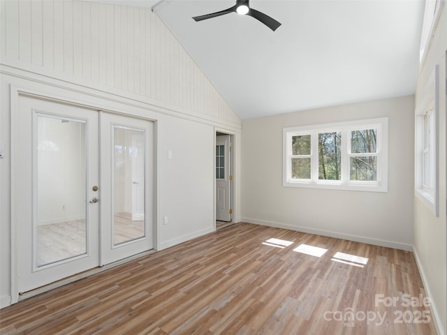 empty room with a ceiling fan, baseboards, high vaulted ceiling, french doors, and light wood-style floors