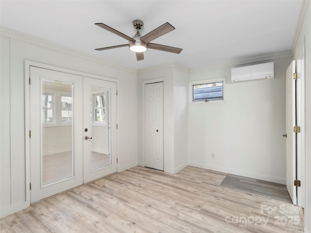 unfurnished bedroom with baseboards, french doors, a wall mounted air conditioner, crown molding, and light wood-type flooring