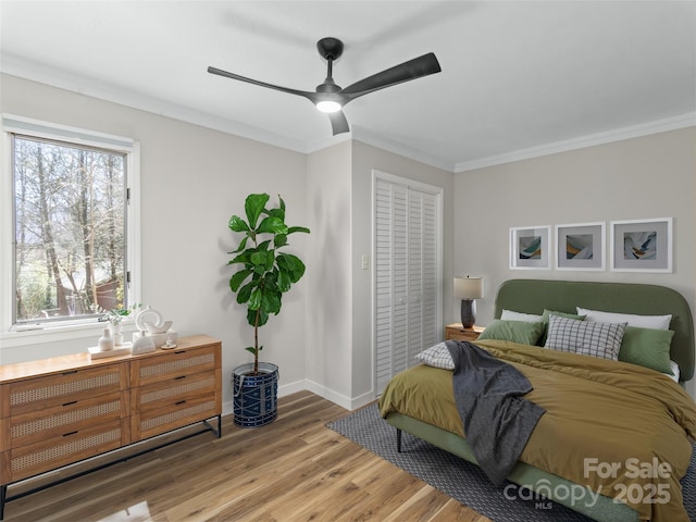 bedroom featuring baseboards, wood finished floors, a closet, and ornamental molding