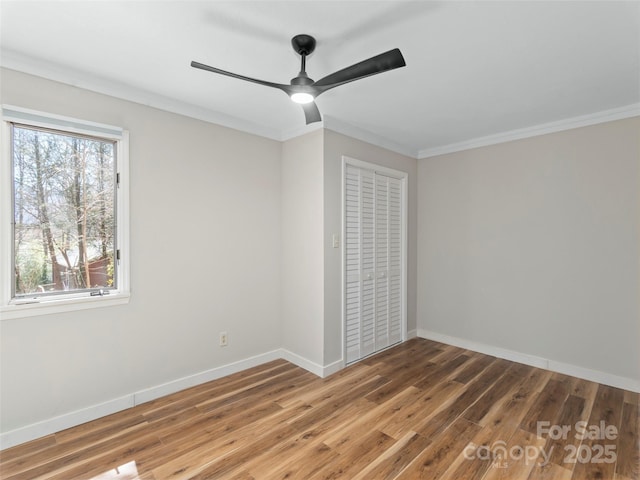 unfurnished room featuring ornamental molding, baseboards, a ceiling fan, and wood finished floors