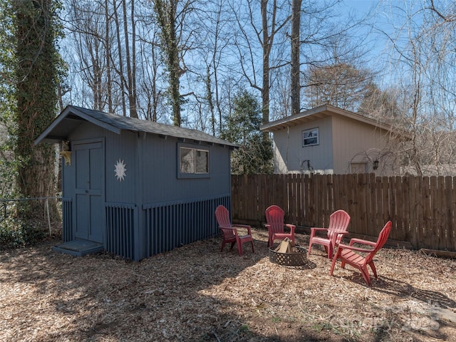 view of yard featuring an outdoor structure, fence, a shed, and an outdoor fire pit