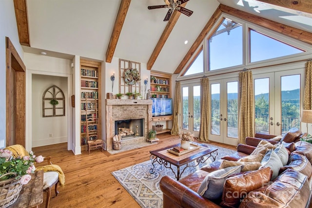 living area featuring a brick fireplace, built in shelves, beamed ceiling, french doors, and hardwood / wood-style flooring