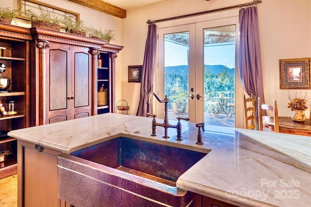 kitchen featuring french doors, light stone countertops, and a sink