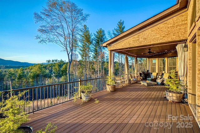 wooden deck featuring a wooded view and a ceiling fan