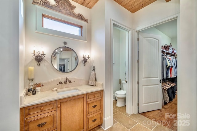 bathroom with vanity, a walk in closet, wooden ceiling, toilet, and tile patterned floors