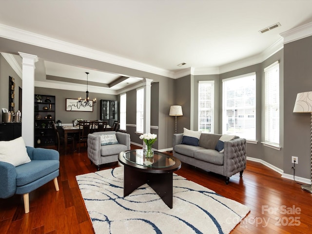 living area featuring visible vents, hardwood / wood-style flooring, baseboards, and decorative columns