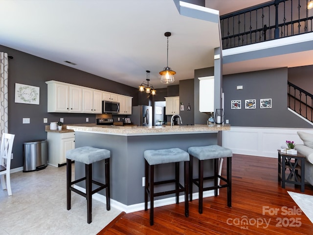 kitchen with white cabinetry, a peninsula, appliances with stainless steel finishes, and a sink