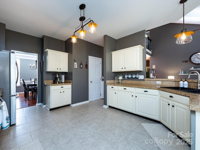 kitchen with a sink, white cabinetry, pendant lighting, and freestanding refrigerator