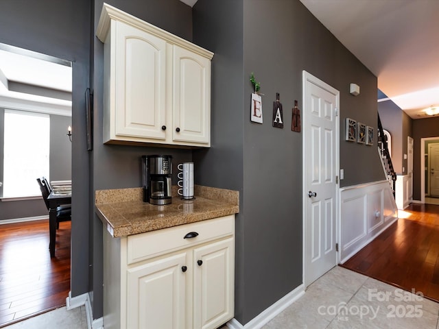 bar with a wainscoted wall and light wood finished floors