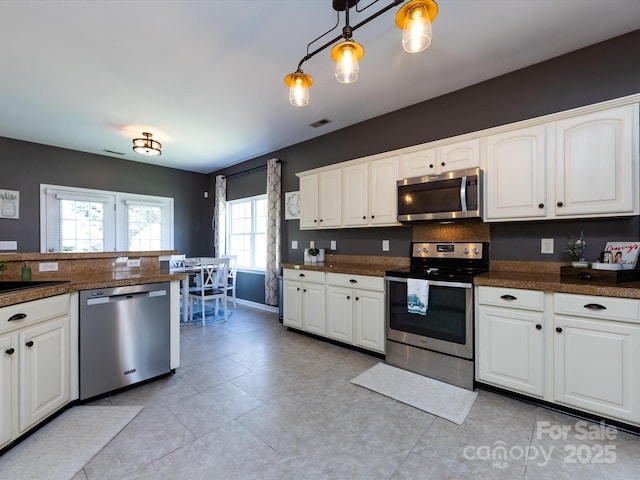 kitchen featuring a sink, appliances with stainless steel finishes, white cabinets, baseboards, and tile counters