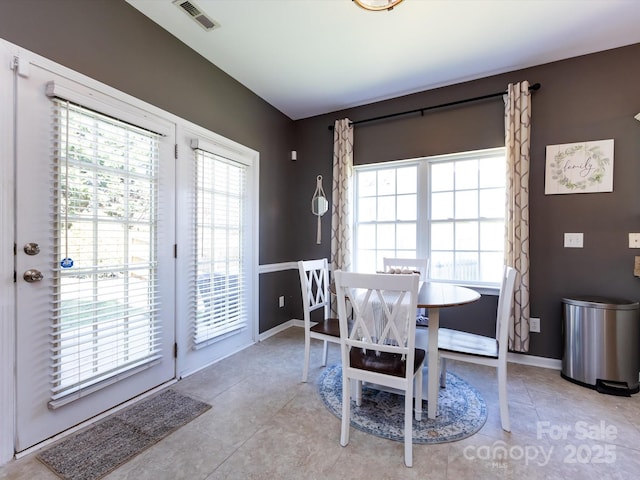 dining space with light tile patterned floors, visible vents, a healthy amount of sunlight, and baseboards