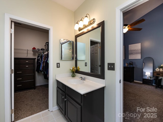 bathroom featuring vanity, a spacious closet, baseboards, and ceiling fan