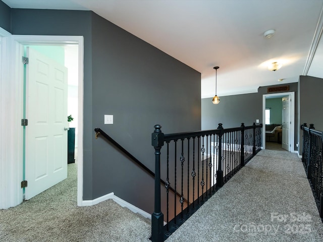 hall featuring an upstairs landing, baseboards, and carpet floors