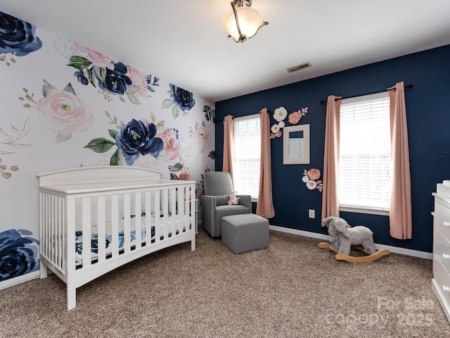 carpeted bedroom featuring visible vents, baseboards, a nursery area, and wallpapered walls