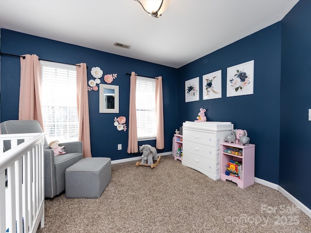 bedroom with multiple windows, a crib, and carpet