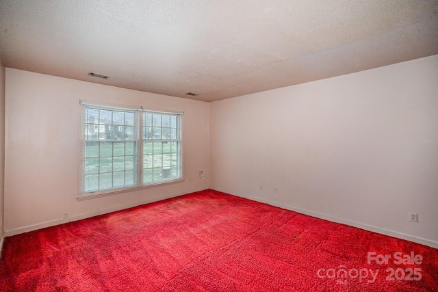 carpeted spare room with baseboards, visible vents, and a textured ceiling