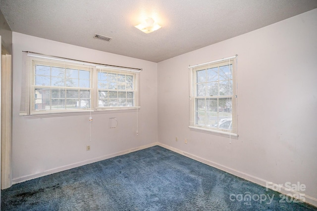 unfurnished room with visible vents, baseboards, a textured ceiling, and dark carpet