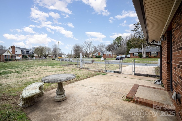 view of yard featuring a patio, a gate, fence, and a residential view