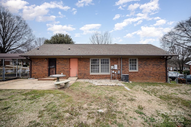 back of property featuring fence, a lawn, brick siding, and roof with shingles