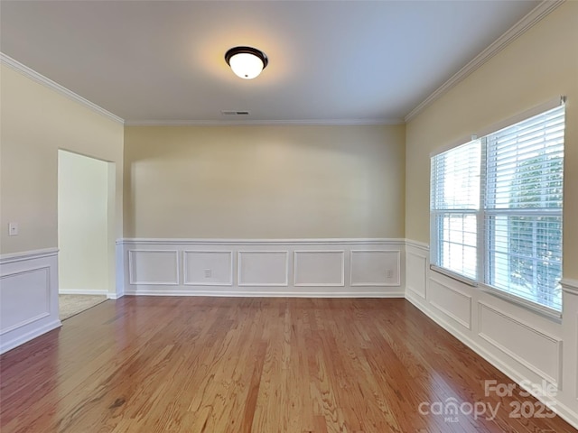 spare room with visible vents, crown molding, and wood finished floors