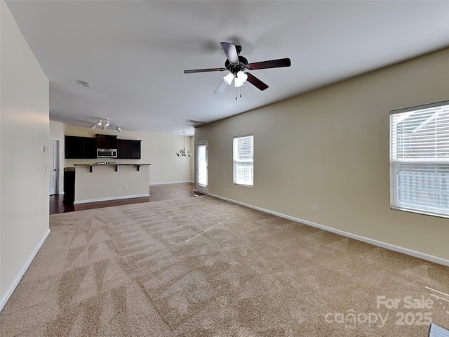 unfurnished living room featuring baseboards, a ceiling fan, and dark colored carpet