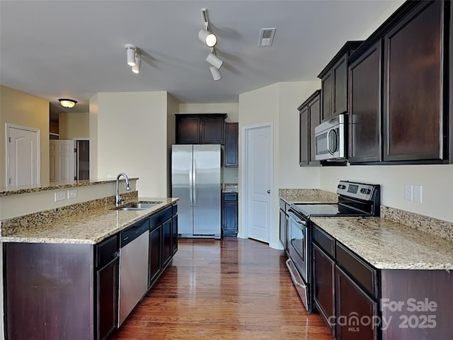 kitchen featuring visible vents, a sink, light stone counters, appliances with stainless steel finishes, and dark wood-style flooring