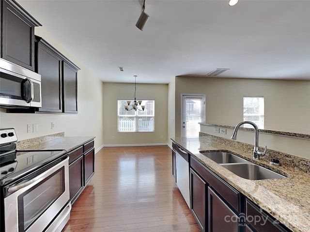 kitchen featuring visible vents, light stone countertops, wood finished floors, stainless steel appliances, and a sink